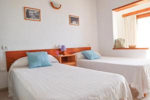伊维萨镇Hostal Marblau Ibiza的配有白色墙壁和蓝色枕头的客房内的两张床