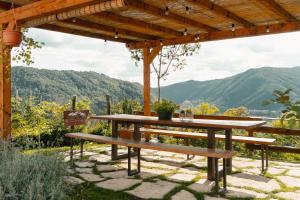 SequsinoAgriturismo Riva dei Coz的木凉棚下的野餐桌和长椅