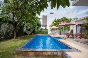 盛日社Cozrum Luxury - Aria Resort Vũng Tàu的庭院内的游泳池,配有桌椅