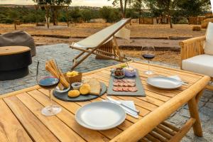 埃斯特雷莫斯Reflexos D'Alma Turismo Rural的一张木桌,上面放着酒杯和食物