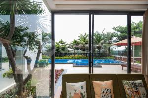盛日社Cozrum Luxury - Aria Resort Vũng Tàu的客厅设有窗户,享有游泳池的景色