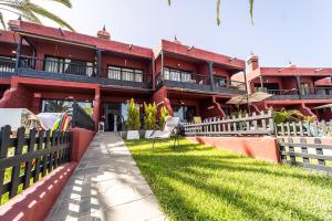 阿吉拉海滩Casa Martín.的一座红色的建筑,有栅栏和院子