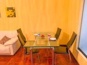 利马Iguana Haus Lima的带沙发的客厅里的玻璃桌子和椅子