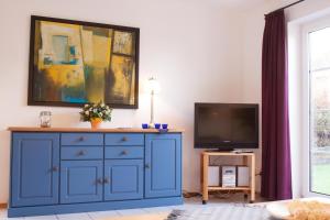 诺德代希Haus Tjalk Ferienhaus Tjalk links的客厅里的蓝色橱柜,配有电视