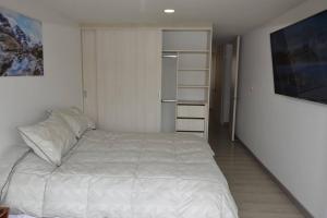 派帕Hermoso apartamento en Paipa con vista al lago Sochagota.的卧室配有白色的床和衣柜。