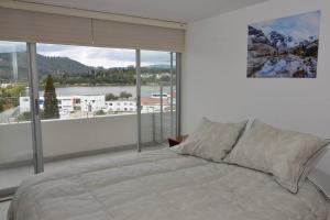 派帕Hermoso apartamento en Paipa con vista al lago Sochagota.的一间卧室设有一张床和一个大窗户