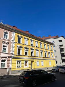 林茨Rudolfquartier Linz, Rudolfstraße的停在黄色建筑前面的黑色汽车