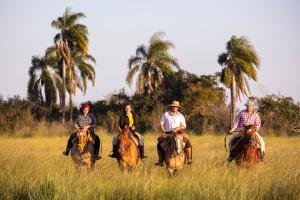 Curuzú CuatiáEstancia San Agustin的一群在田野里骑马的人