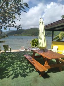 乌图罗阿VILLA DE LA BAIE RAIATEA的一张带雨伞的野餐桌和野餐长凳