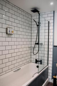 沃明斯特乔治旅店 的浴室设有带玻璃淋浴的浴缸
