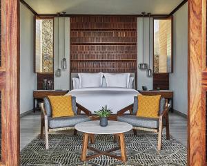 CihuatlánFour Seasons Resort Tamarindo, México的一间卧室配有一张床、两把椅子和一张桌子