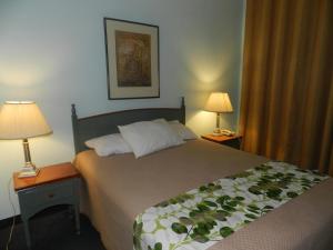 多瓦尔奥伯格机场酒店的一间卧室配有一张大床,桌子上放着两盏灯