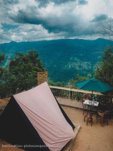 巴杜勒The Cliff Tea Glamping的甲板上的帐篷、桌子和遮阳伞