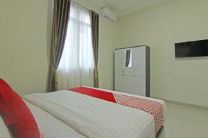 巴东Capital O 91675 Utama Residence的一间卧室配有一张带红白毯子的床