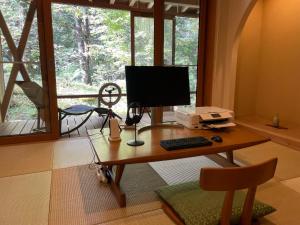 高山奥飞驒温泉乡旅馆（仅限成人入住）的窗户房间里一张桌子和一台电脑