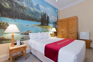 珀斯European Hotel的酒店客房,配有一张床和一幅山画