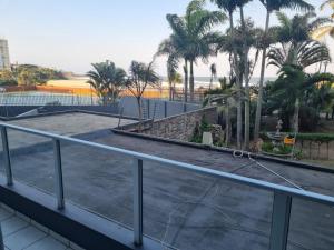 马盖特Margate Beachfront Apt for 6 adults 2 kids的一个带棕榈树和海滩阳台的网球场