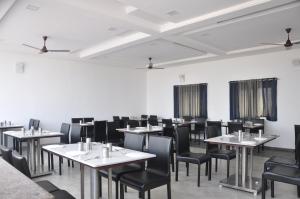亨比Hotel SSLR ,Gangavathi的用餐室配有白色桌子和黑色椅子