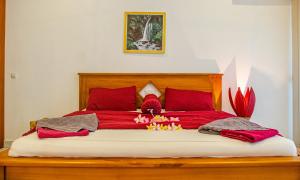 圣吉吉Senggigi Homes & Apartments的一张红色的大床,上面有红色的枕头和鲜花