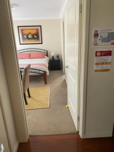 卧龙岗Private room with ensuite and parking close to Wollongong CBD的一间卧室设有一张床,门通往走廊
