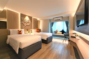 清迈Moose Hotel Nimman的酒店客房设有两张床和窗户。