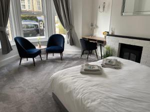 伊斯特布恩Impeccable 2-Bed Apartment in Eastbourne的一间卧室配有一张床和椅子,以及一个壁炉