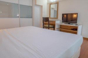 峇六拜The CEO Executive Suites的卧室配有白色的床和电视。
