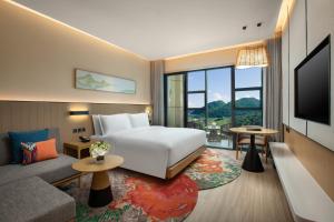 贵阳贵阳青岩假日度假酒店的酒店客房配有床、沙发和电视。