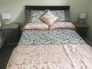 阿马Dympna's City Centre apartment, Armagh的一张带粉红色和灰色床罩的床和两张床头柜