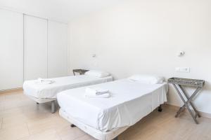 贝尼多姆Apartamentos La Rosita Old Town B-21的配有白色墙壁和木地板的客房内的两张床