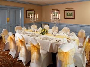 利文斯顿利文斯顿美居酒店的宴会厅配有长桌、椅子和弓
