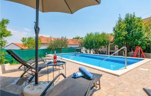 RunovićCozy Home In Runovic With Outdoor Swimming Pool的一个带桌子和遮阳伞的游泳池