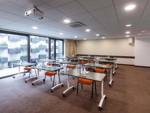 布洛泽姆Mercure Bale Mulhouse Aeroport的一个带桌椅的教室,位于带窗户的房间