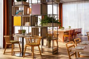 日内瓦IntercityHotel Geneva的餐厅设有木椅和桌子,种有植物