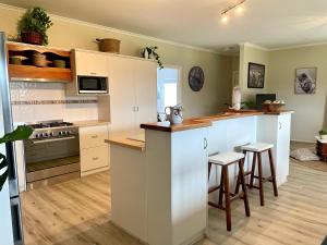 金斯科特Yorks View的厨房配有白色橱柜和带凳子的台面