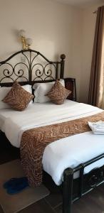 内罗毕Sochati Casa Resort的一间卧室配有一张大床,提供棕色和白色的枕头