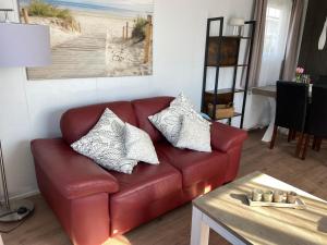 塞罗斯凯尔克Chalet Oceanside Zeeland的客厅里一张红色的皮沙发,配有桌子