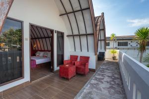 吉利特拉旺安Kidi's Lodge Gilitrawangan的一个带红色椅子和一张床的阳台以及一间卧室