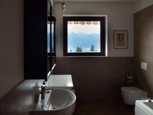勒威诺Amazing 3 bedrooms villa with lavish garden, breathtaking lake and mountains view的一间带水槽和卫生间的浴室以及窗户。