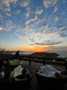 布希奥斯Pousada Mirante dos Papagaios的一群人坐在甲板上欣赏日落