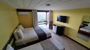 布希奥斯Pousada Mirante dos Papagaios的酒店客房设有两张床和电视。