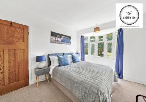 剑桥3 Bedroom House with Parking & Garden By Cherry Inn Short Lets & Serviced Accommodation Cambridge的一间卧室配有一张带蓝色枕头的床和一扇门