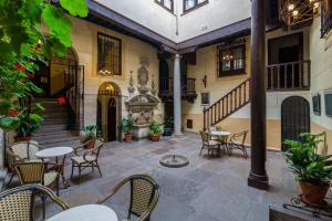 格拉纳达皮内达马里亚纳宫酒店的庭院配有桌椅和喷泉