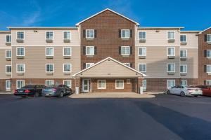 代顿Extended Stay America Select Suites - Dayton - Miamisburg的一座大型砖砌建筑,停车场内有车辆停放