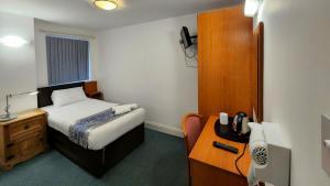 海斯SK Heathrow Hotel的小房间设有一张床和一张带电话的书桌