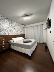 南雅拉瓜Pousada Central Jaraguá的一间卧室配有一张床和一台电视。