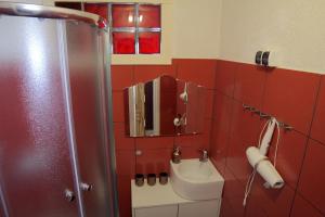 里加Mini cinema & movie studio with PS5的红色的浴室设有水槽和淋浴