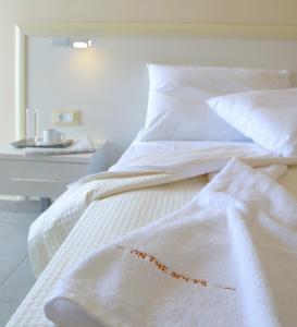 帕琉乔拉岩石之上酒店的一张带白色毯子的床,上面写着床单