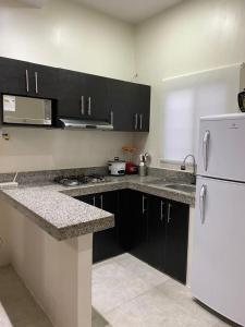 萨利纳斯Villa en Salinas vía Punta Carnero的厨房配有黑色橱柜和白色冰箱。