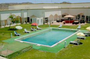 IbrāOYO 142 Al Sharqiya Sands Hotel的庭院里的大型游泳池,配有椅子和遮阳伞